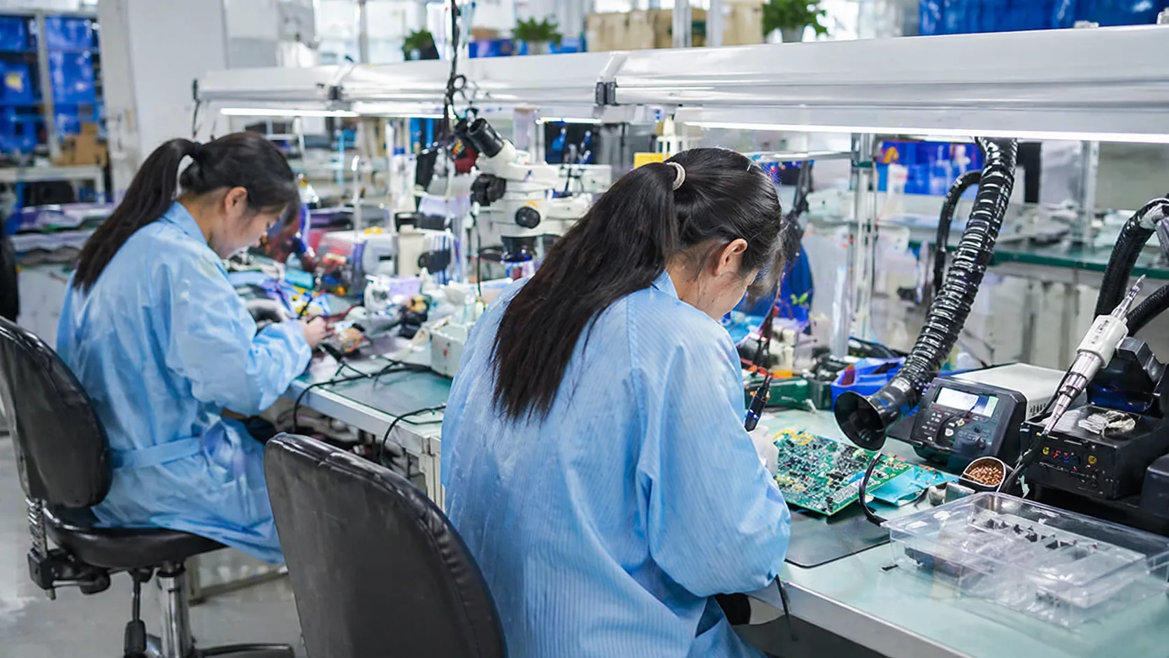 PCB assembly technicians working on circuit boards at production workstations